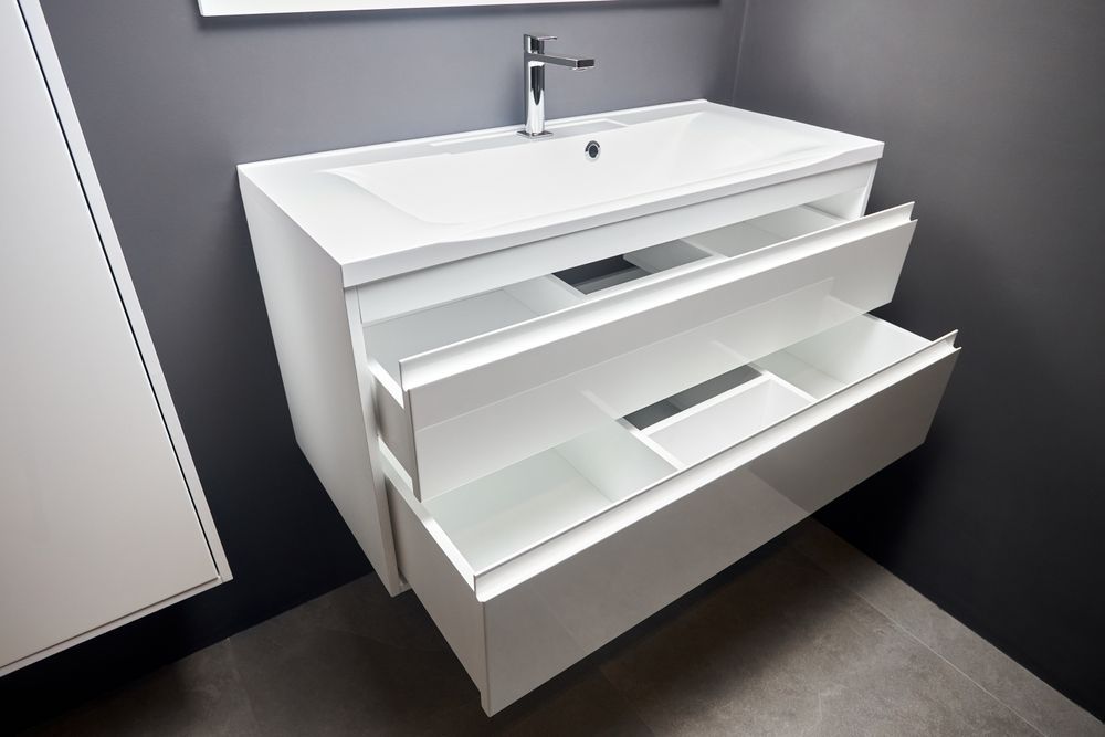 White floating bathroom vanity with two open drawers, chrome faucet, and rectangular sink.