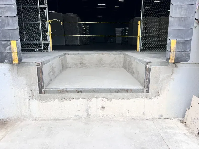 Concrete loading dock bay with a recessed rectangular opening and metal edges, viewed from the exterior.