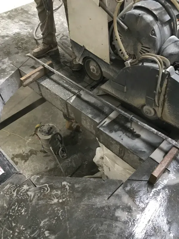 A construction saw cuts through a concrete slab on a job site floor.