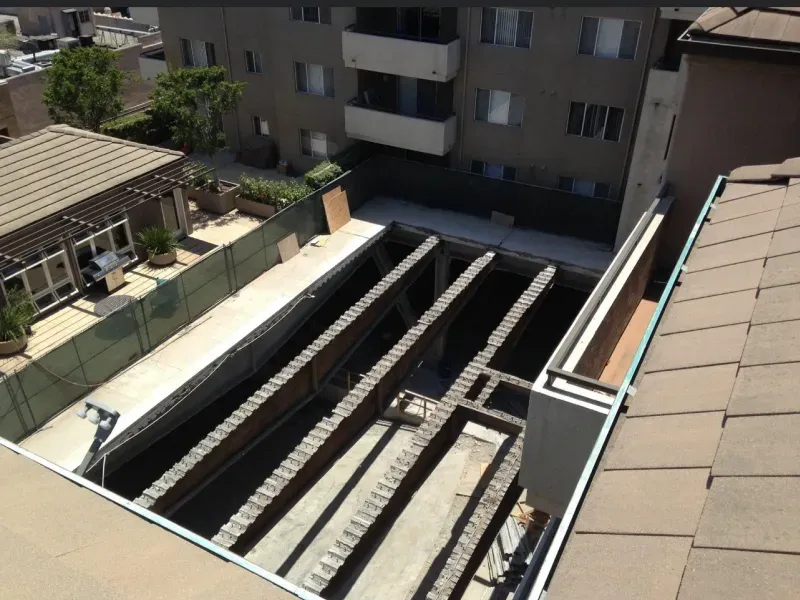 A high-angle view of a rectangular construction trench with exposed brick support columns at a residential site.
