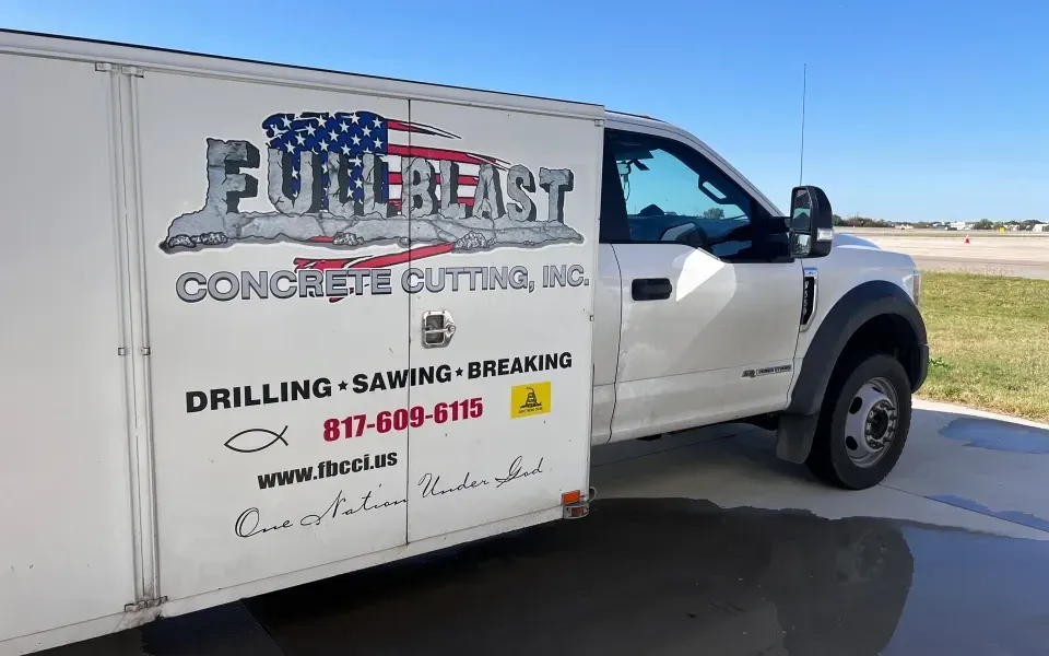 A white work truck parked on a concrete lot features branding for Fullblast Concrete Cutting, Inc. with contact details.