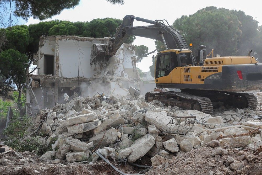 Excavator Demolishes a White Building, Debris and Trees Are in The Setting — Walsh Demolition Pty Ltd in Byron Bay, NSW