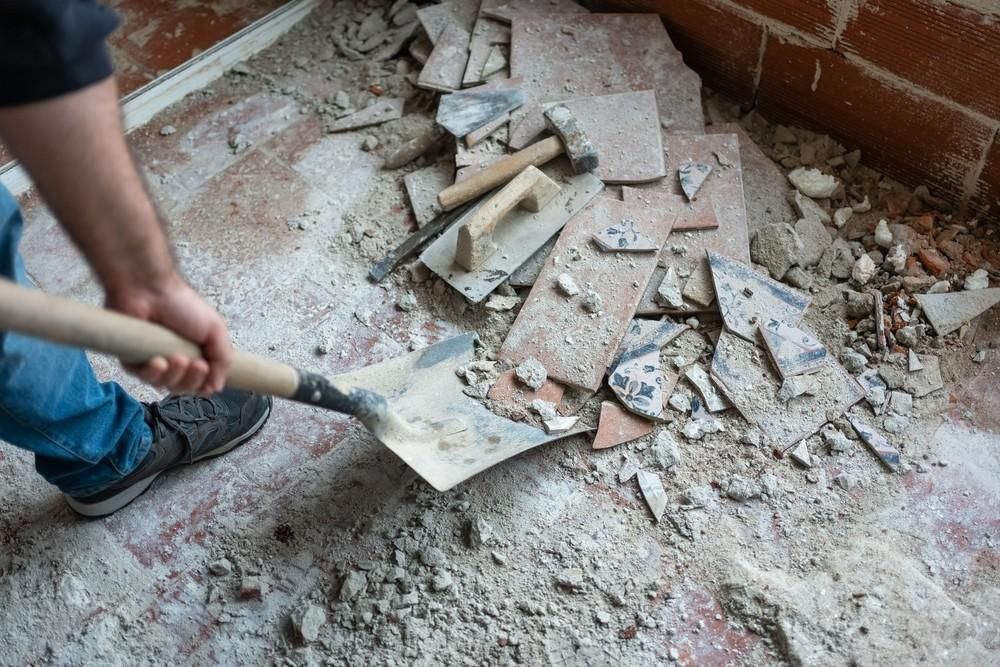 Person Using a Shovel to Remove Debris from A Floor — Walsh Demolition Pty Ltd in Coffs Harbour, NSW