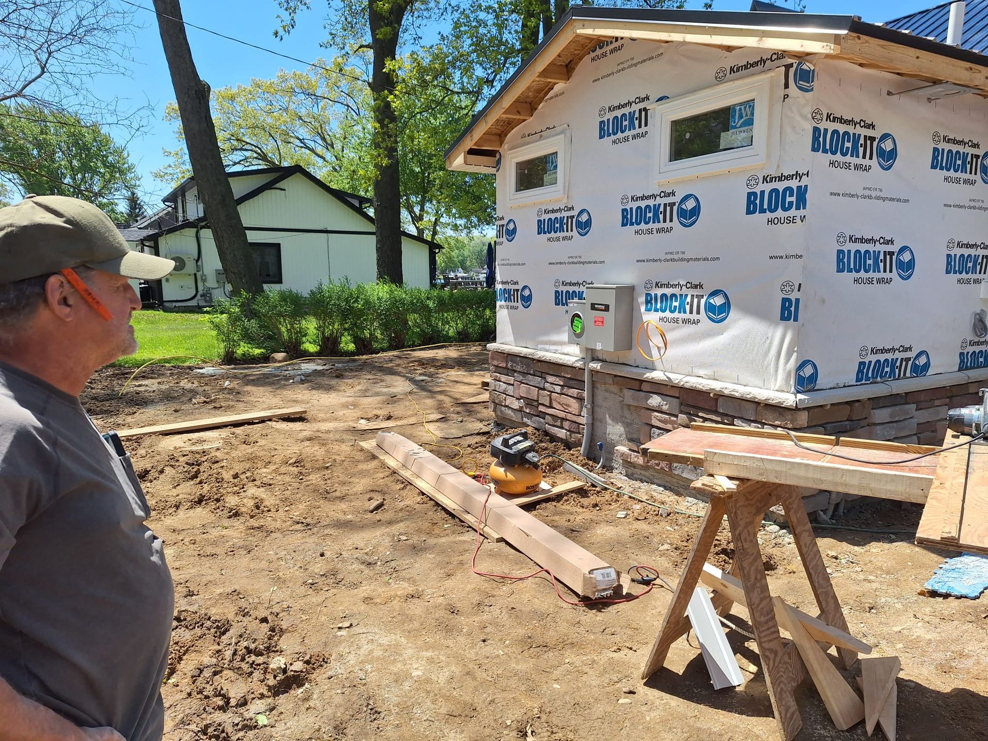 A man is standing in front of a house that is being built.