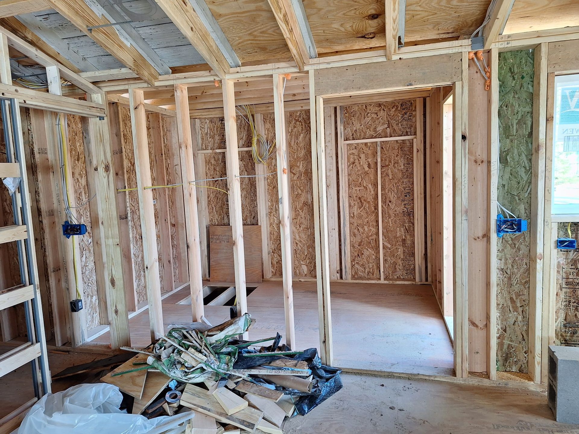 A room in a house under construction with wooden beams and a ladder.