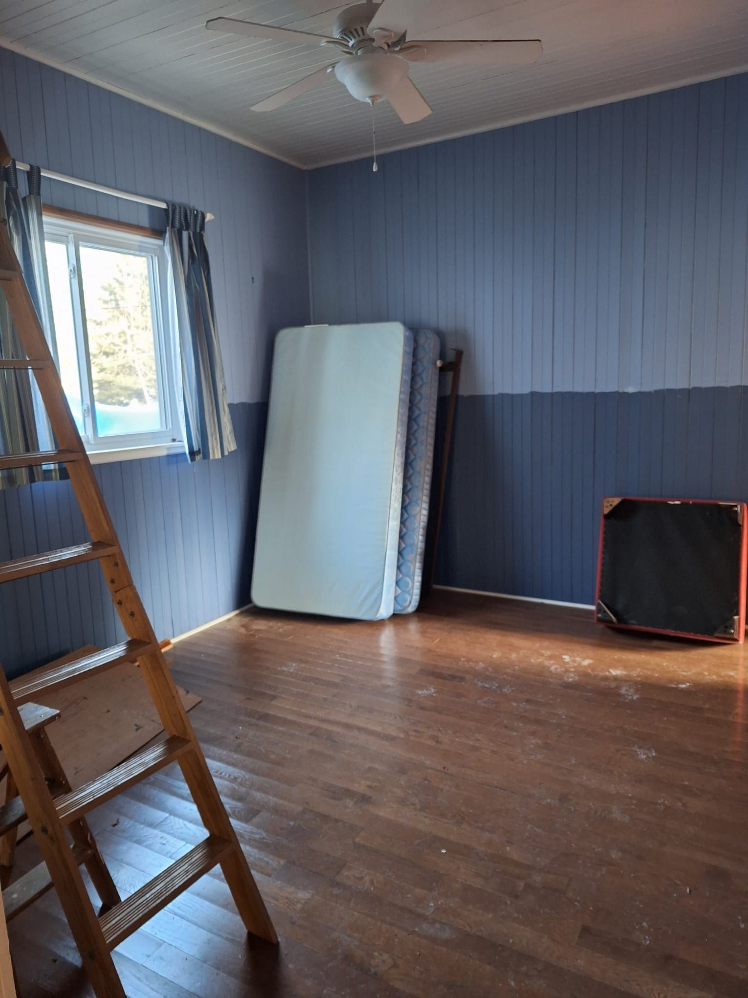 An empty room with a ladder and a mattress on the floor