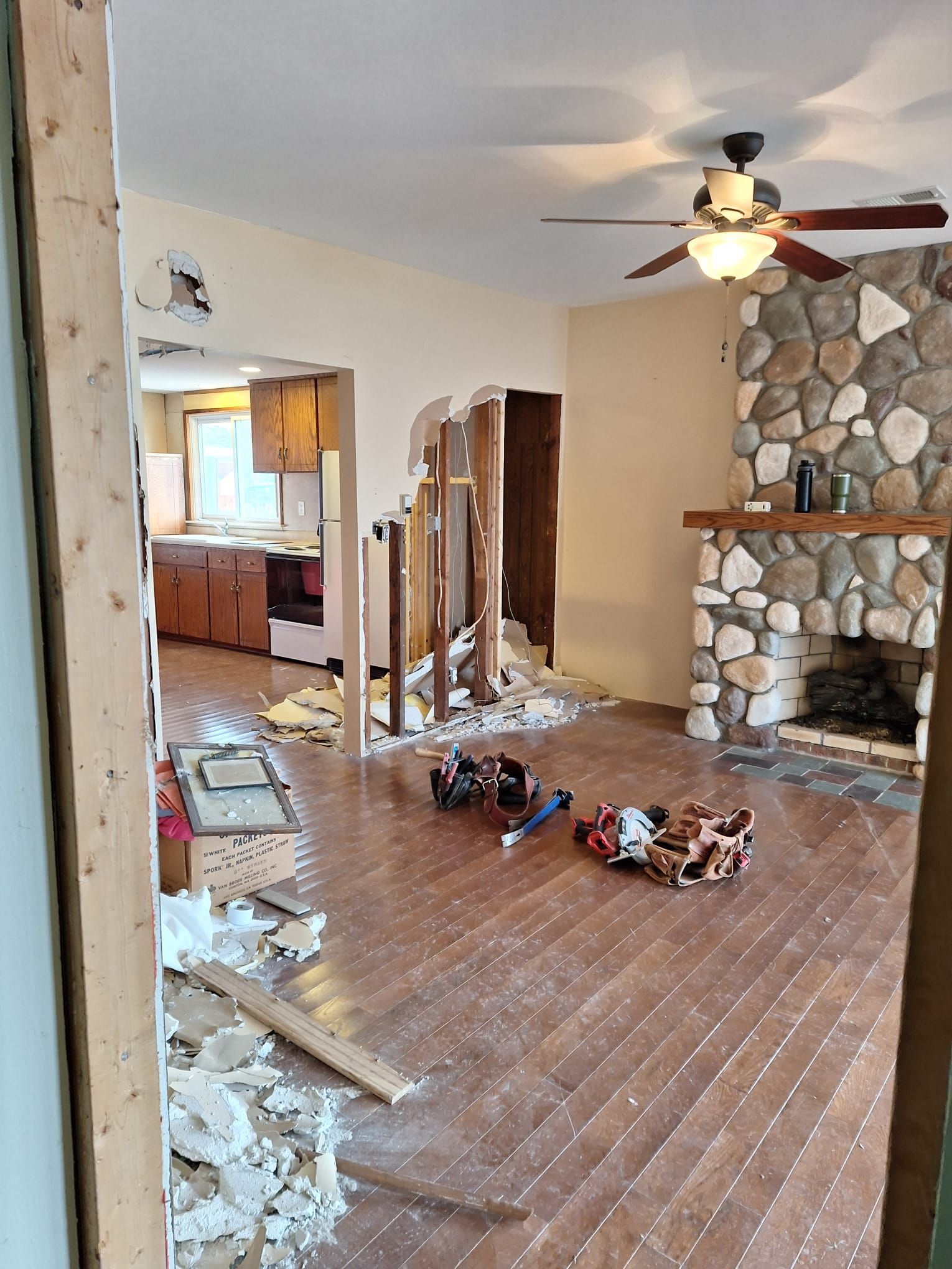 A living room with a ceiling fan and a stone fireplace.