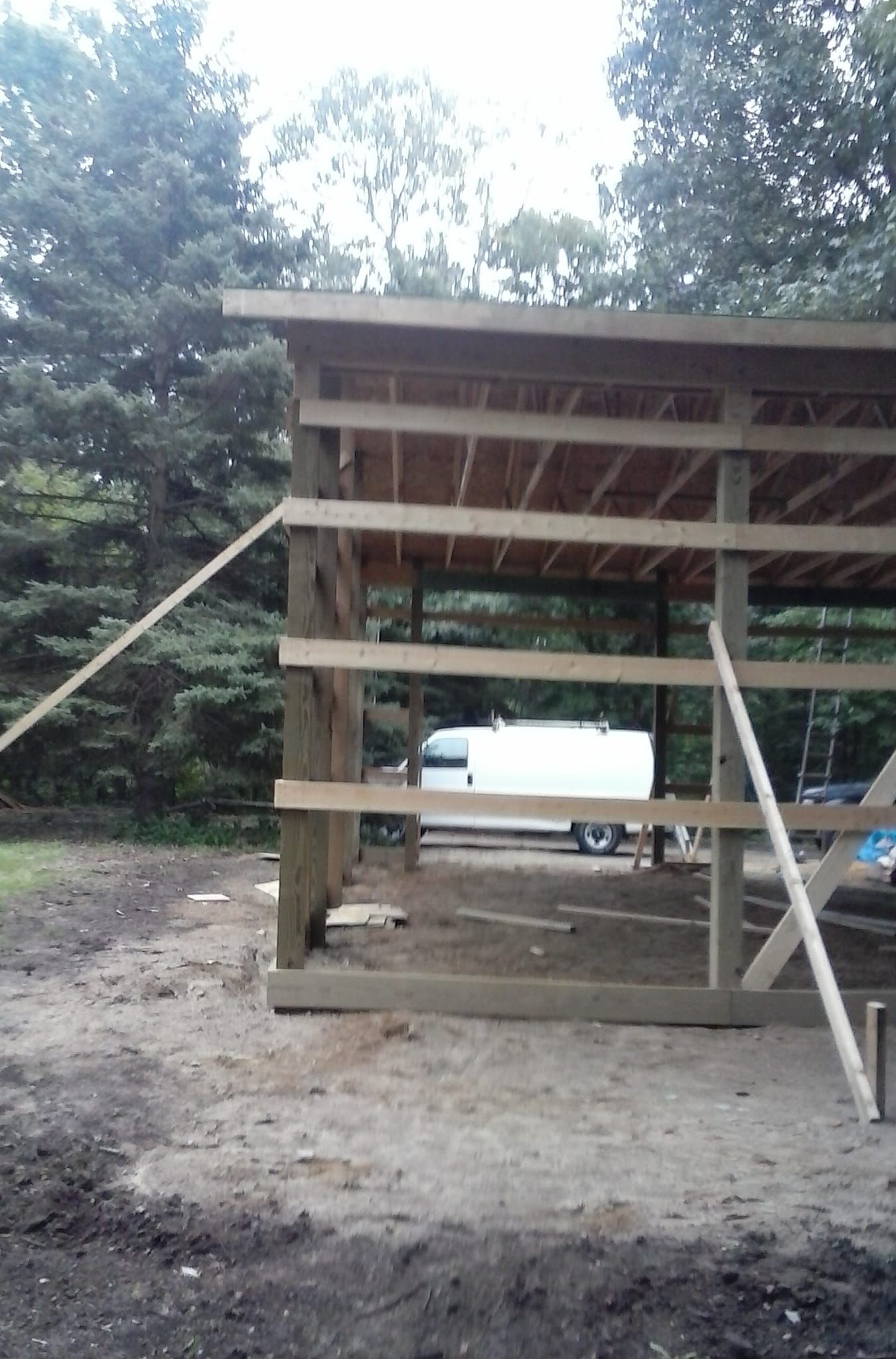 A white van is parked in front of a wooden structure