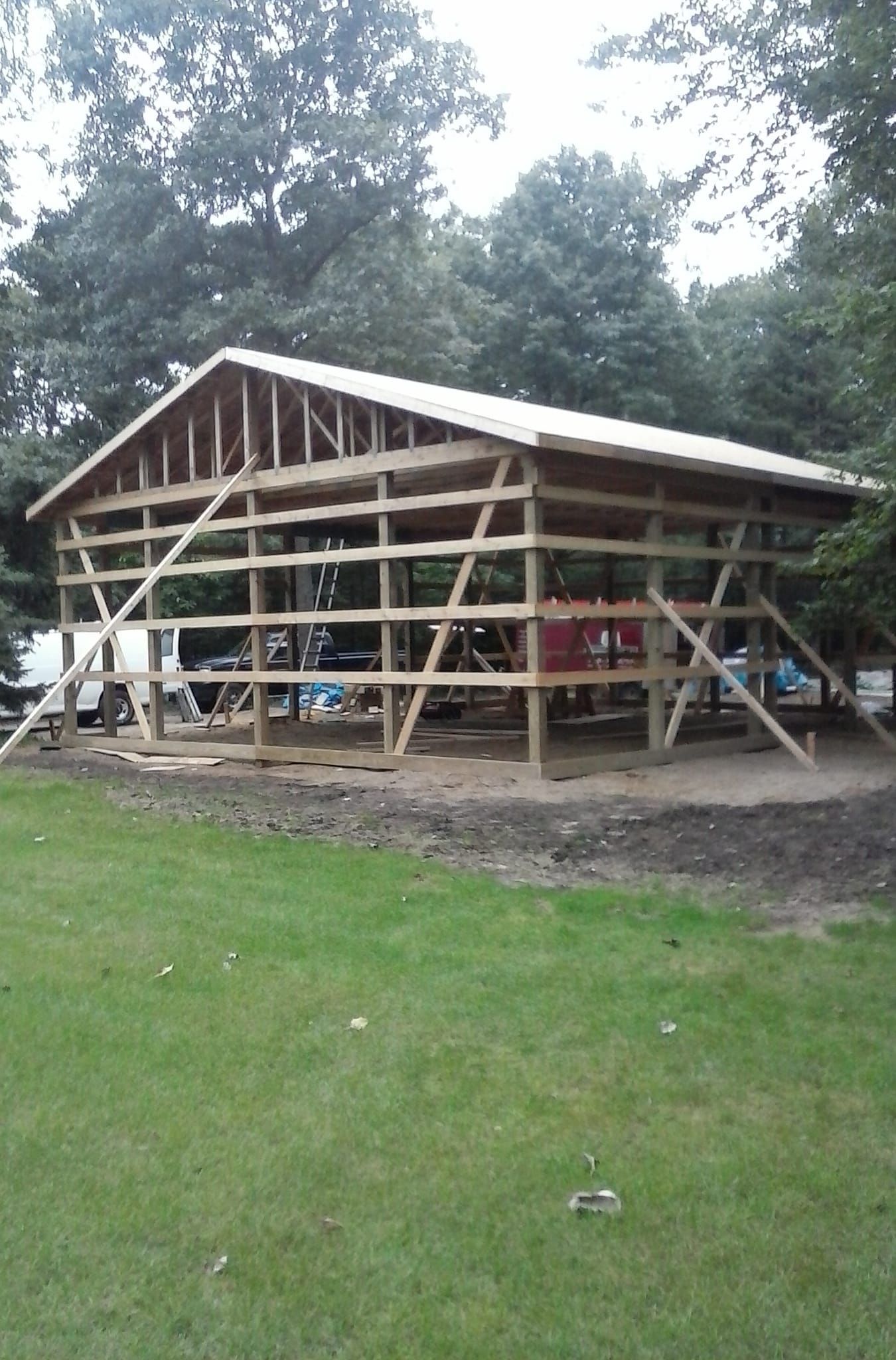 A large wooden structure is being built in the middle of a grassy field.