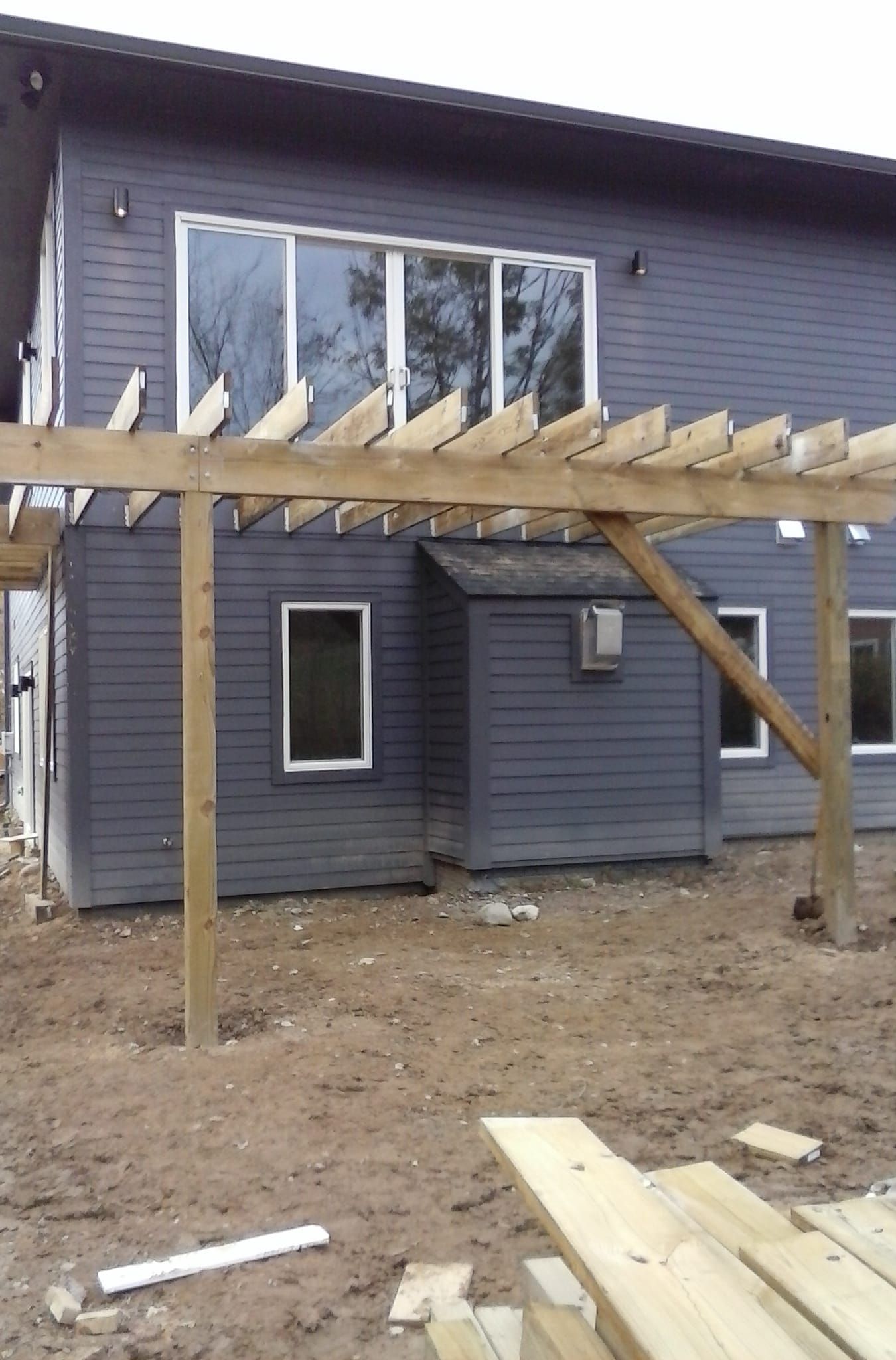 A gray house with a wooden pergola in front of it