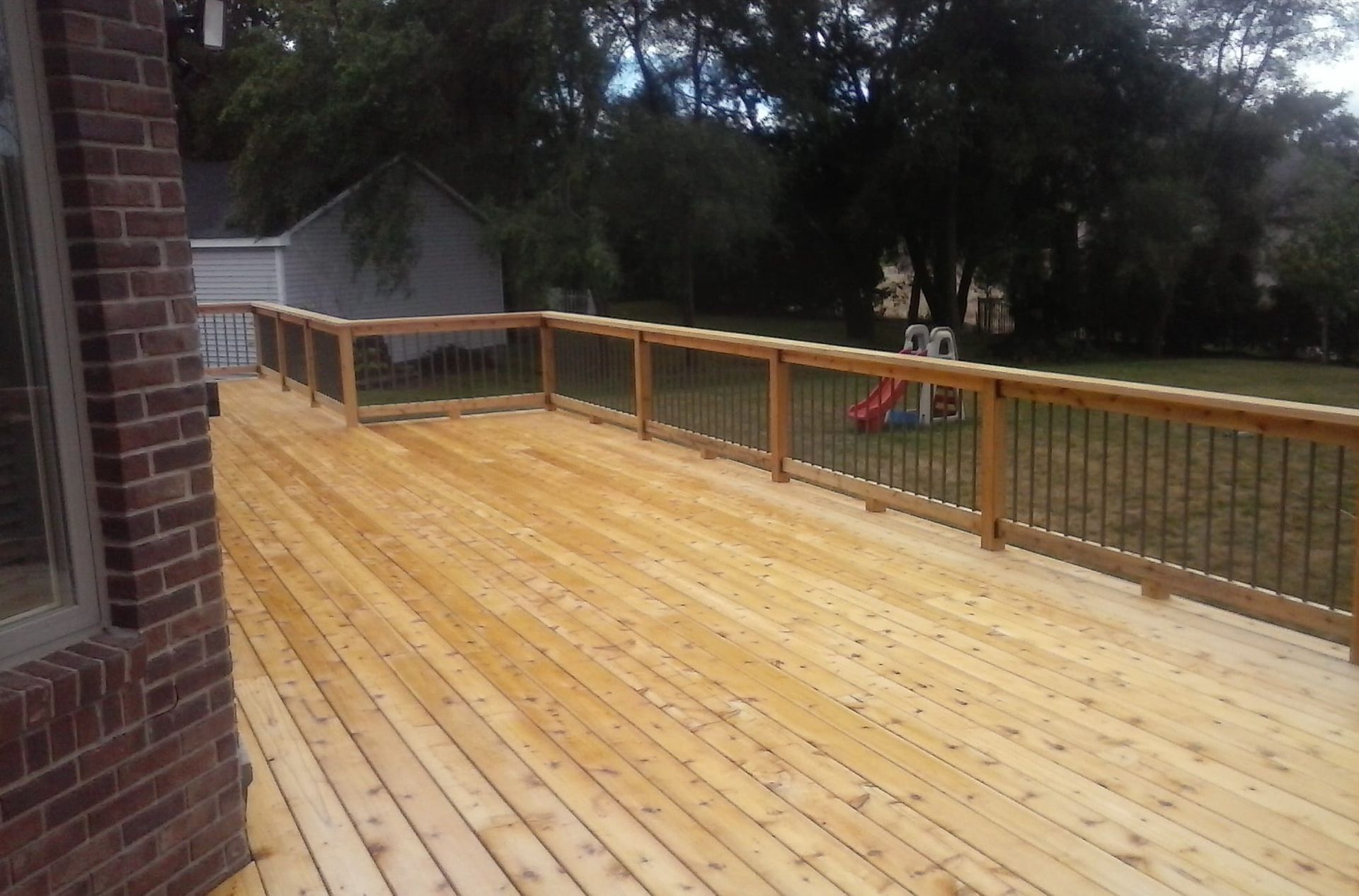 A large wooden deck with a brick building in the background