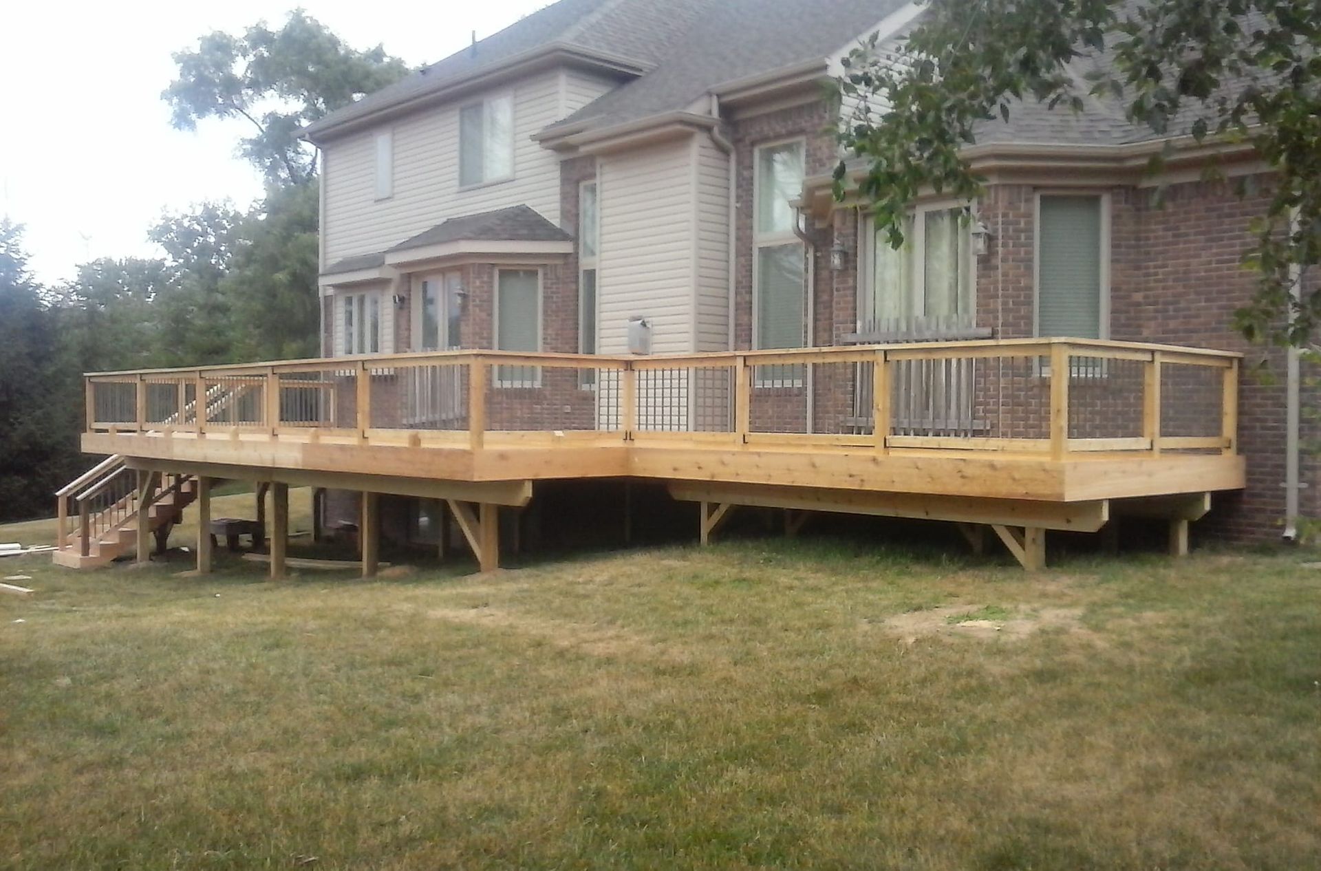 A large wooden deck sits in front of a brick house