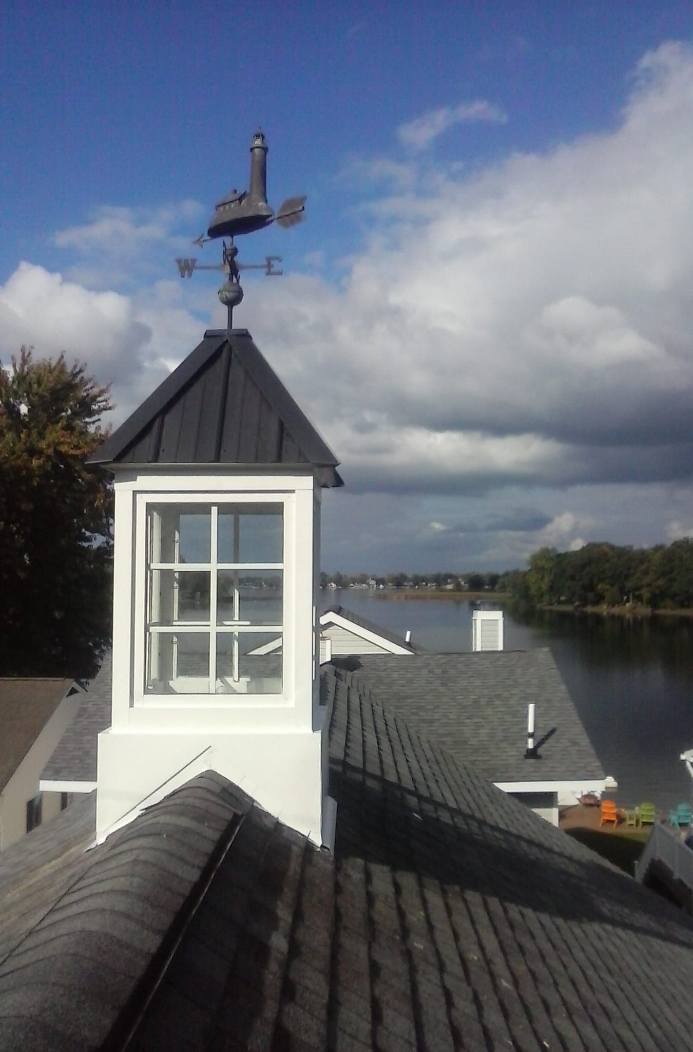 A weather vane on top of a building overlooking a body of water