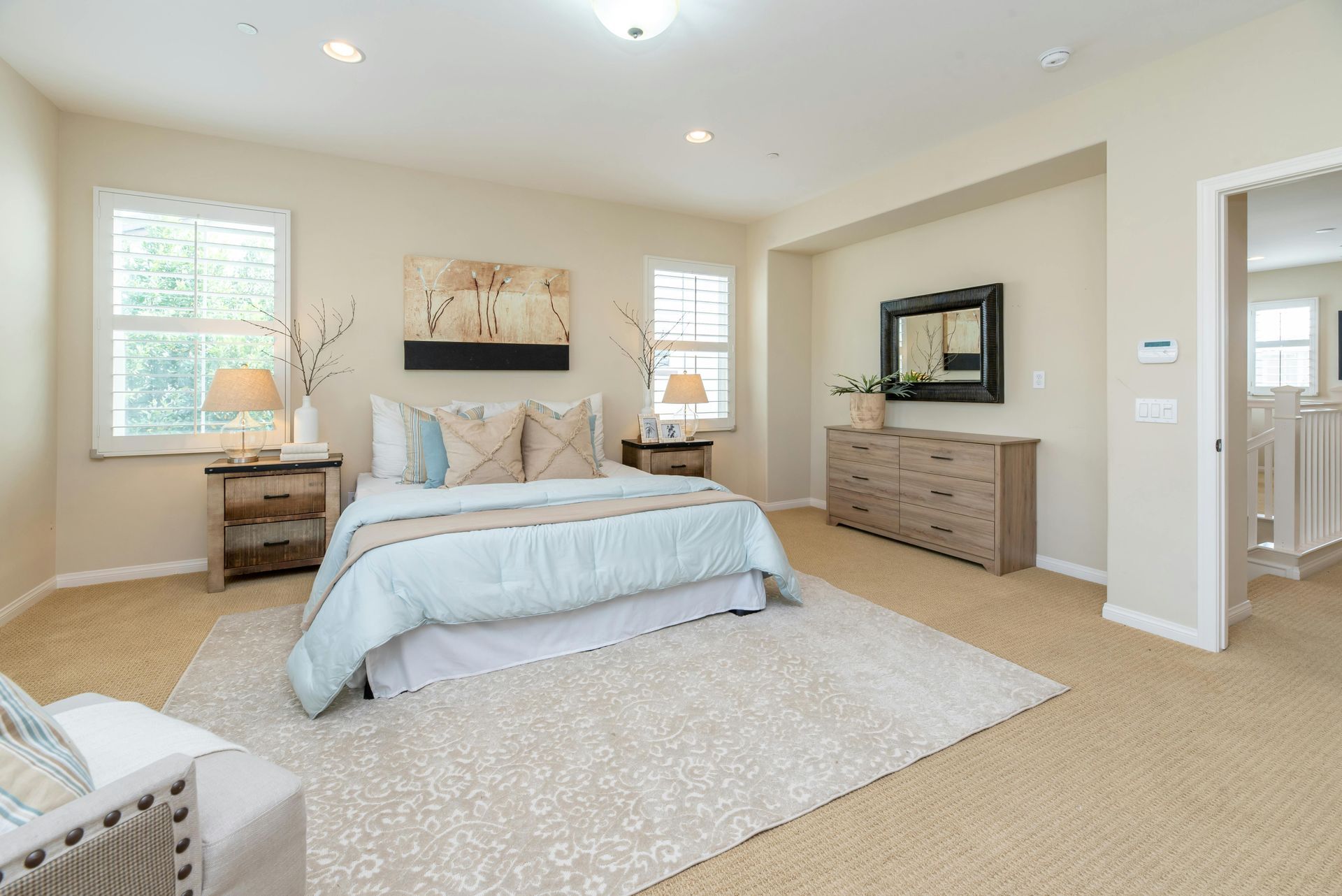 A bedroom with a bed , dresser , nightstand , chair and rug.