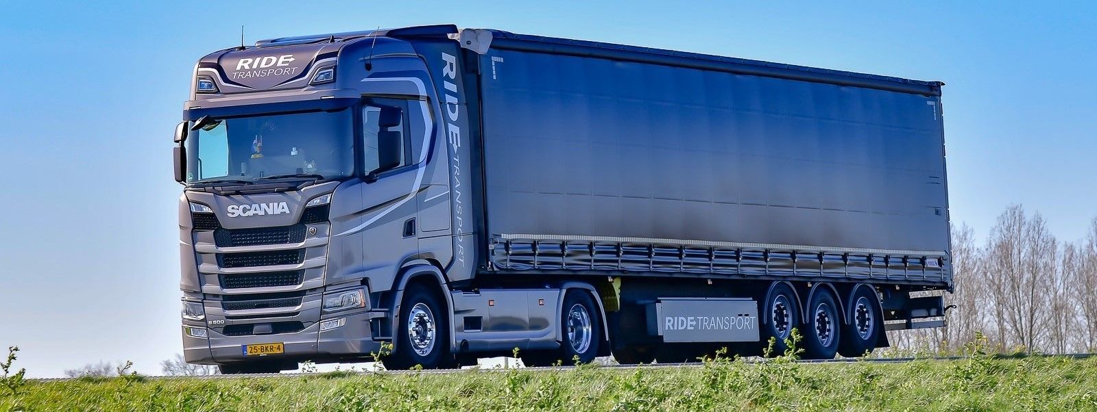 Een grote vrachtwagen rijdt op een zonnige dag over de snelweg.