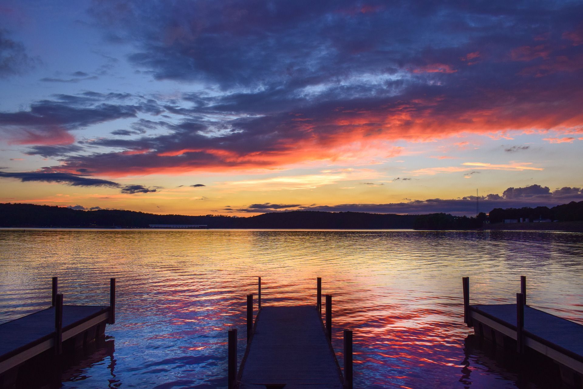 Sunset over lake reflecting vibrant colors; docks in foreground.