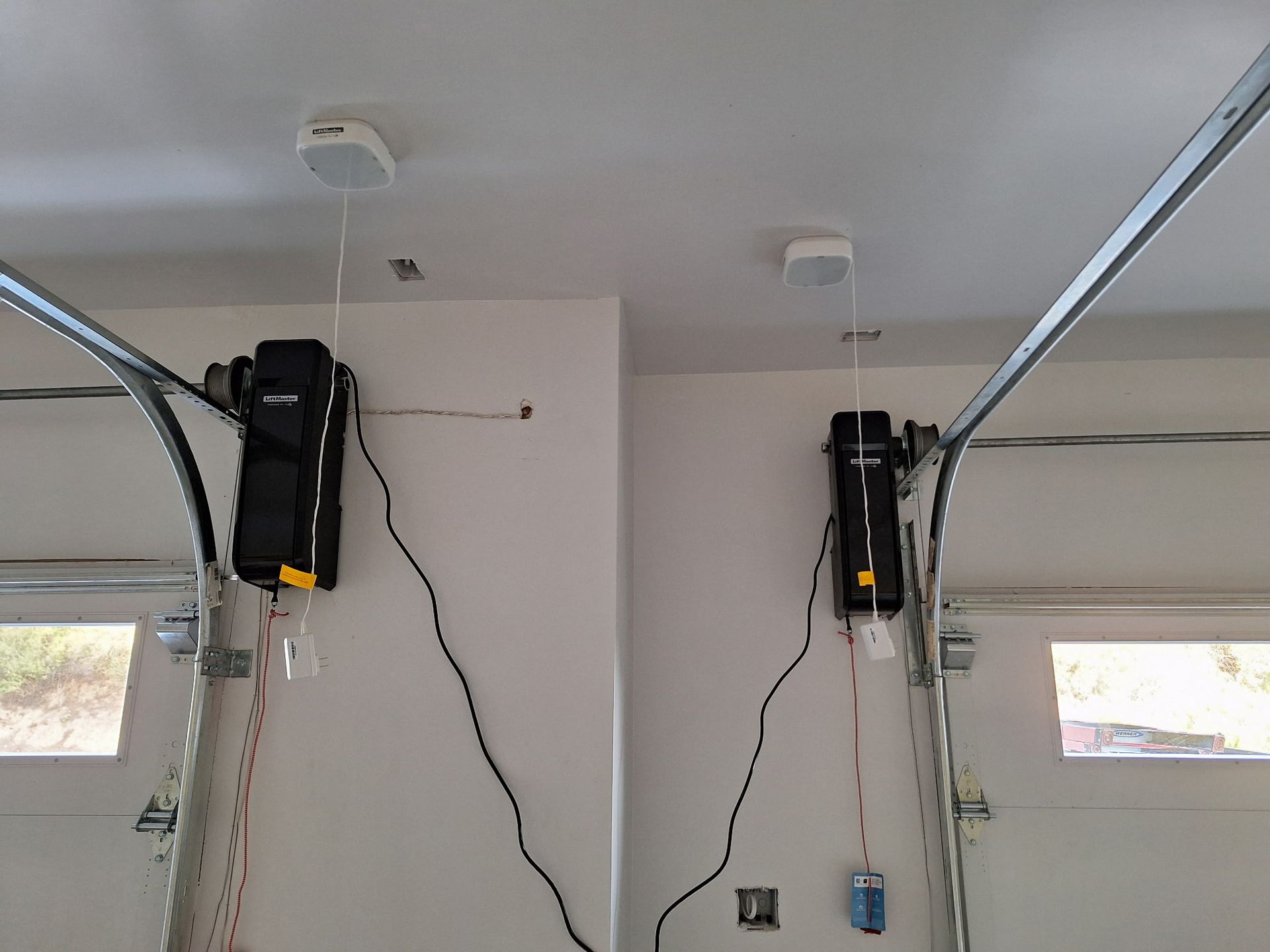 Two garage doors are lit up at night in a dark parking lot.