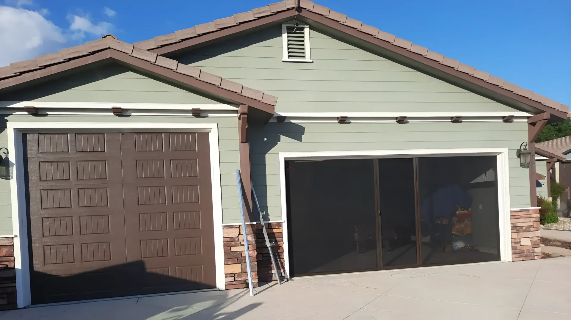 There are three garage doors on the side of a building.
