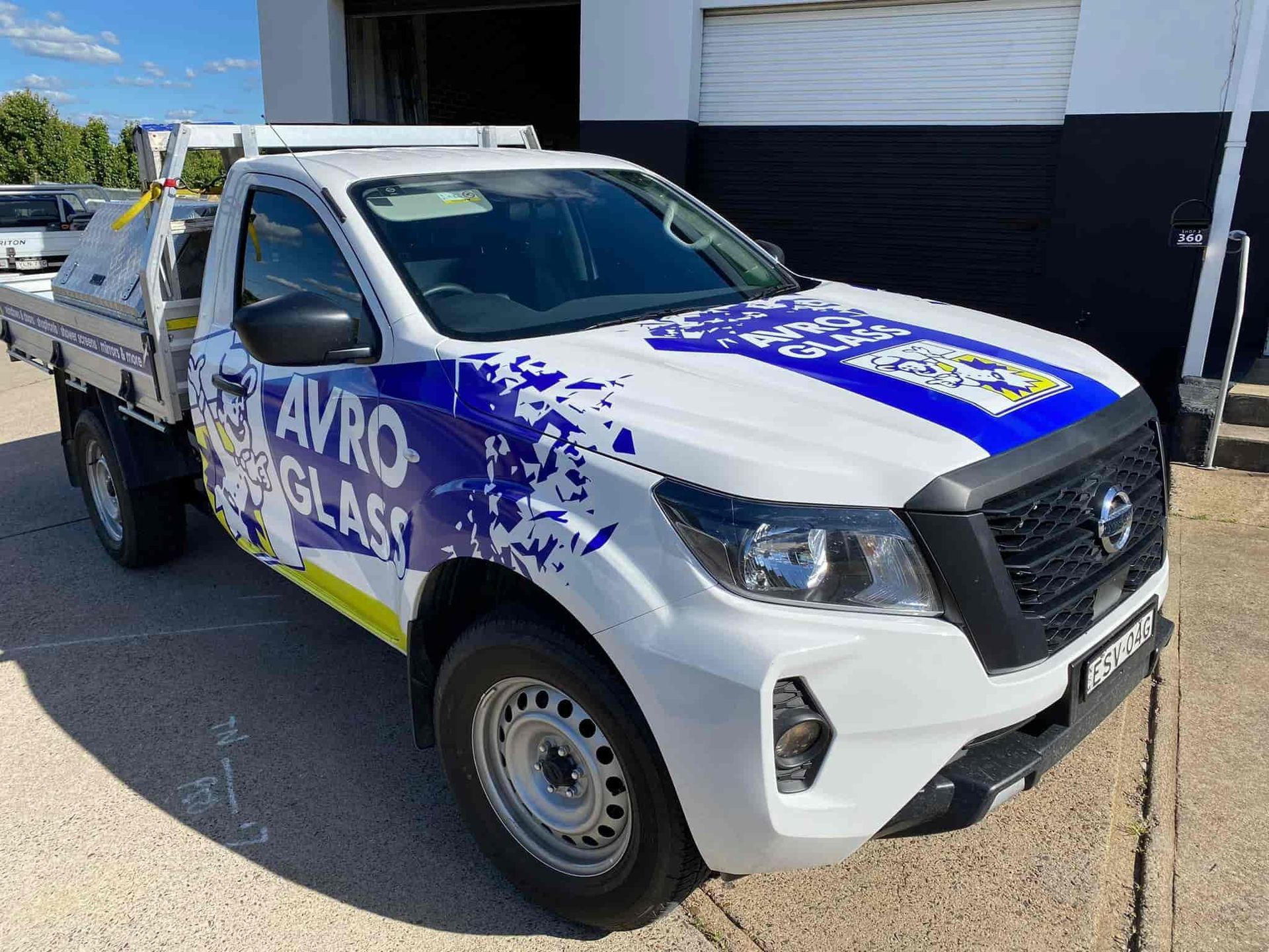 A white truck with a blue stripe on the side is parked in front of a building — McKnight Signs In Hillvue, NSW