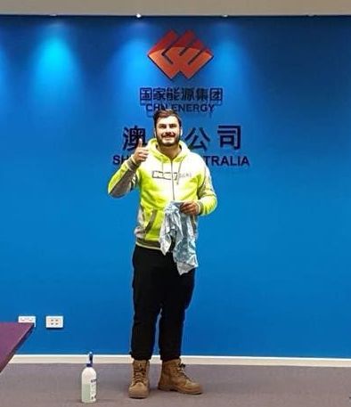 A man in a yellow jacket is standing in front of a blue wall — McKnight Signs In Hillvue, NSW