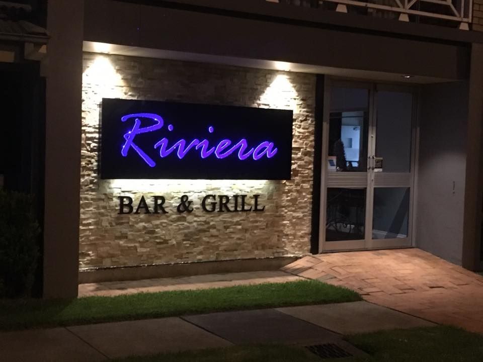 A sign for riviera bar and grill is lit up at night — McKnight Signs In Hillvue, NSW