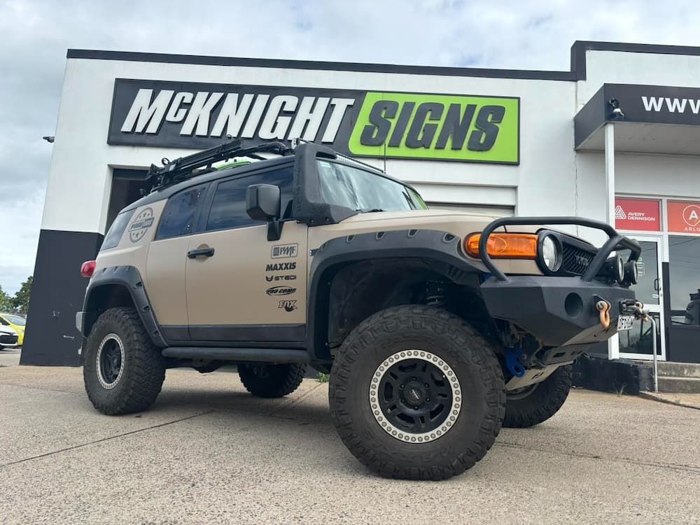 A Tan Toyota Fj Cruiser is Parked Beside a Sign