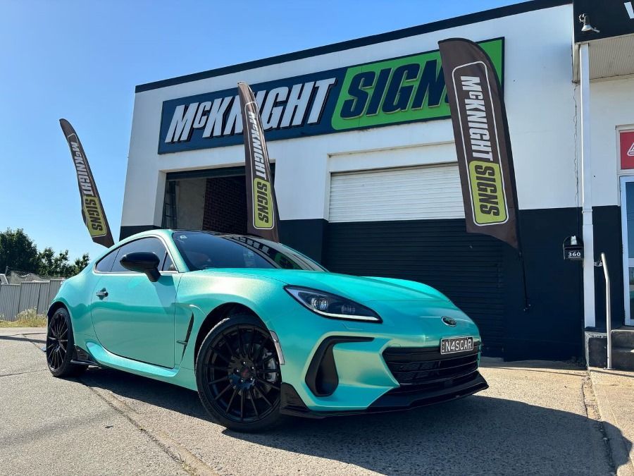 Blue sports car parked outside McKnight Signs store