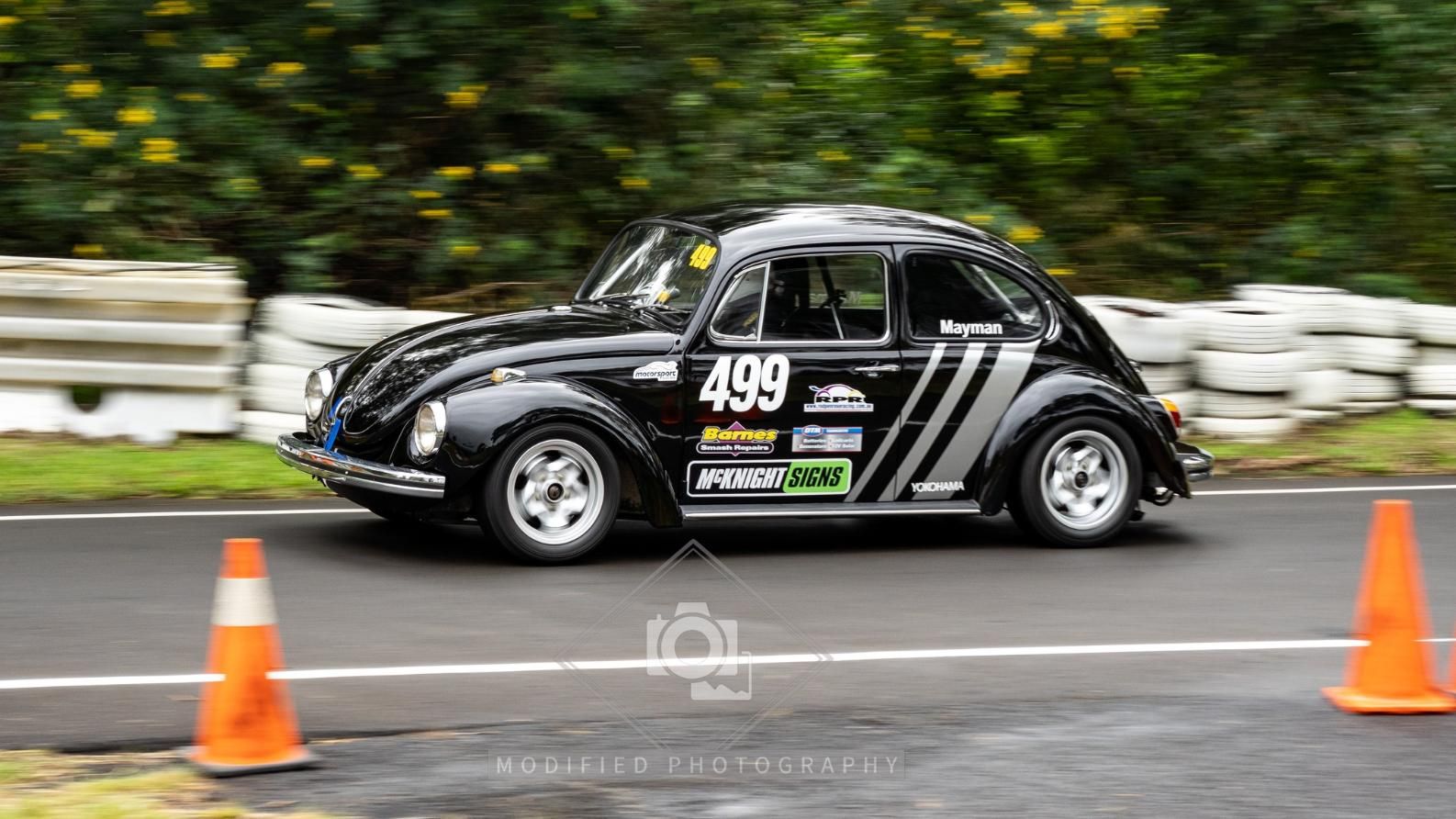 A Black Beetle Is Driving Down A Road Next To Orange Cones — McKnight Signs In Hillvue, NSW