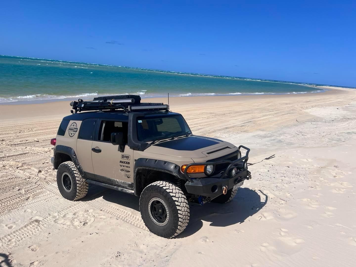 A Toyota Cruiser Is Parked On The Beach Near The Ocean — McKnight Signs In Hillvue, NSW