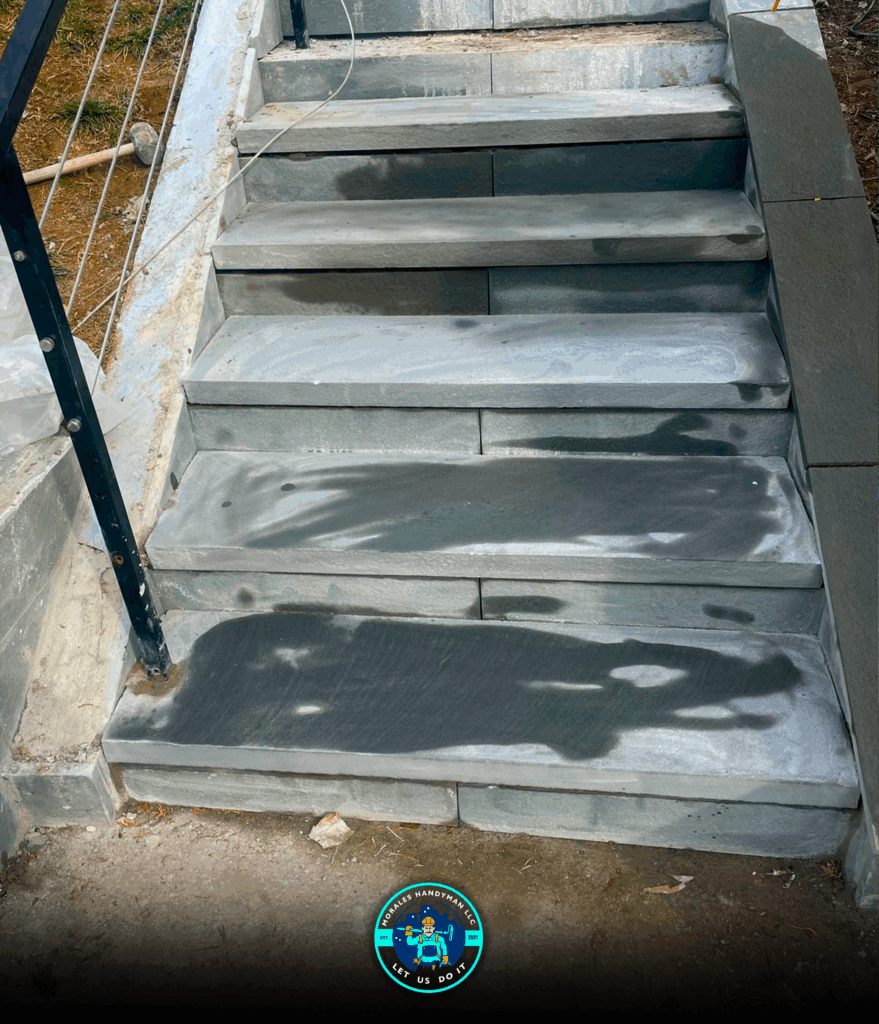 Stone steps leading upwards, with a black metal railing on the left.