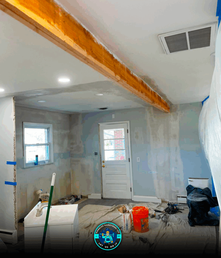 Room undergoing renovation, with exposed wood beam, unfinished walls, and scattered tools.
