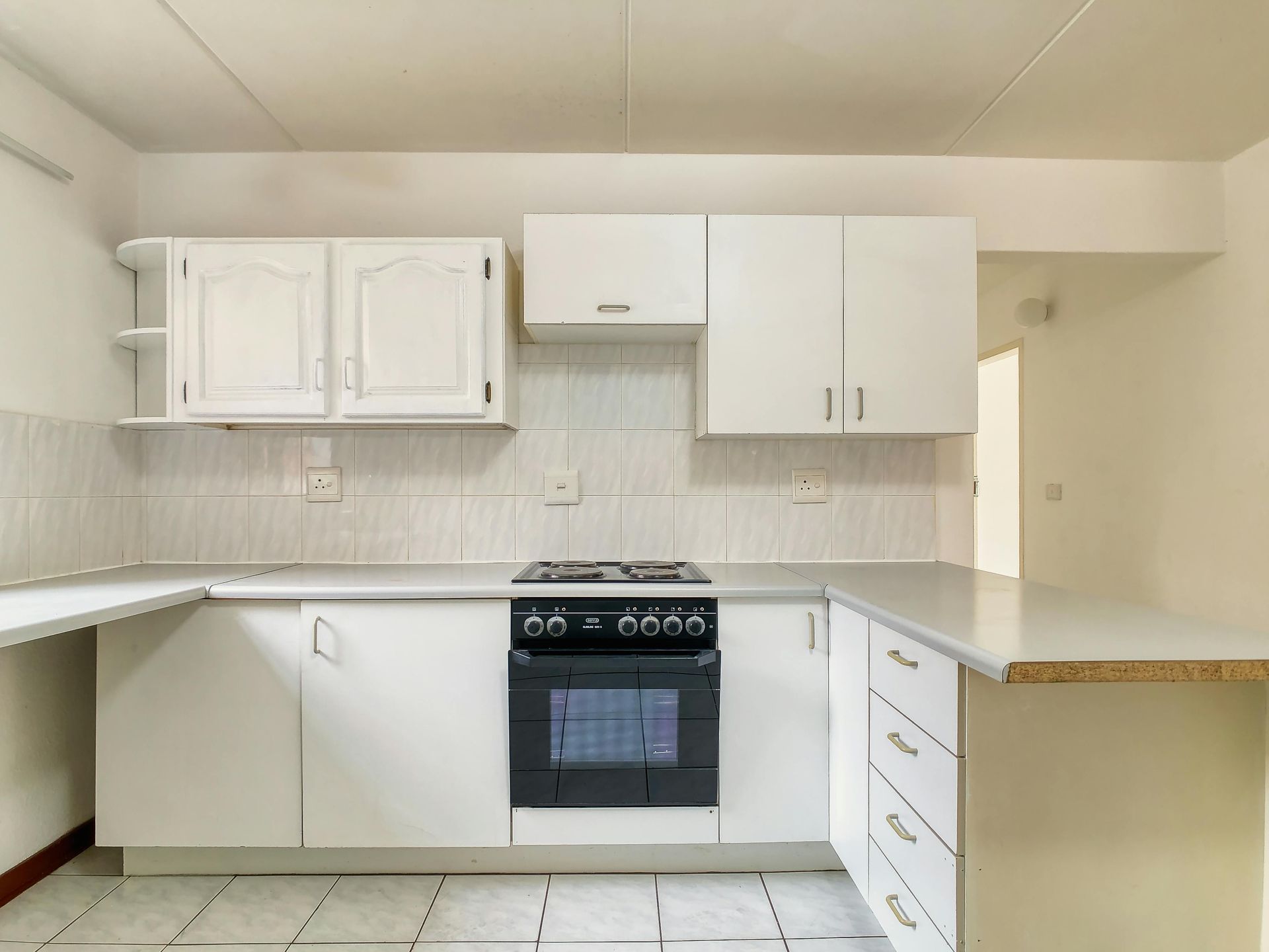 White kitchen with stove, cabinets, and counter.