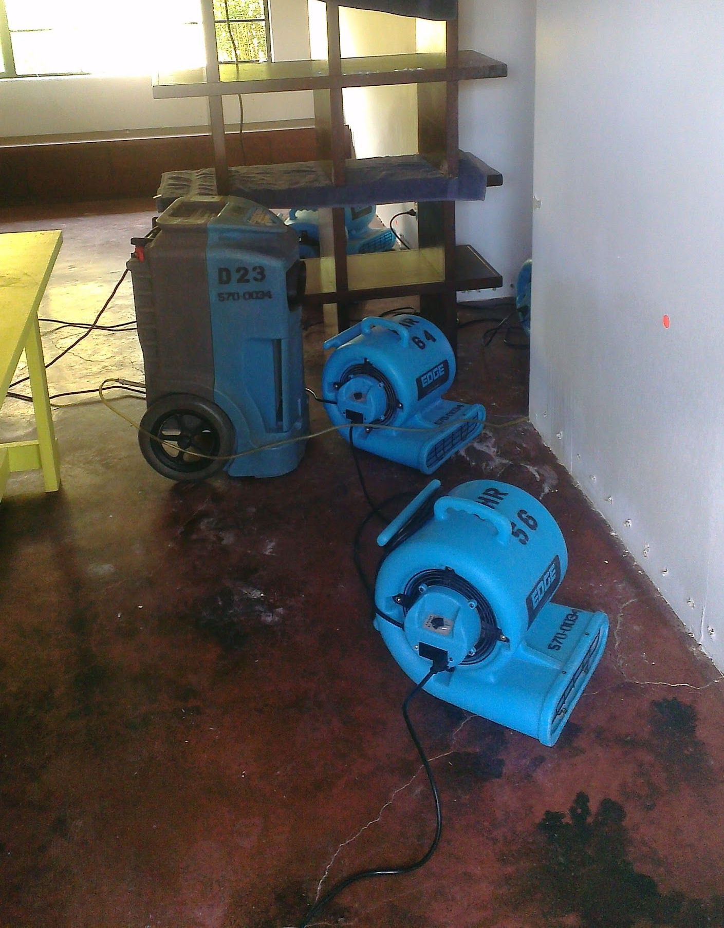 Blue air movers and dehumidifier in a room with water damage.