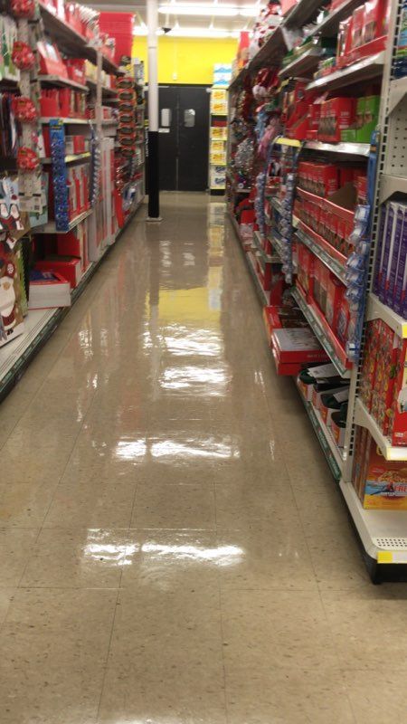 Grocery store aisle; shelves stocked with red-packaged items. Empty floor reflects overhead lights.