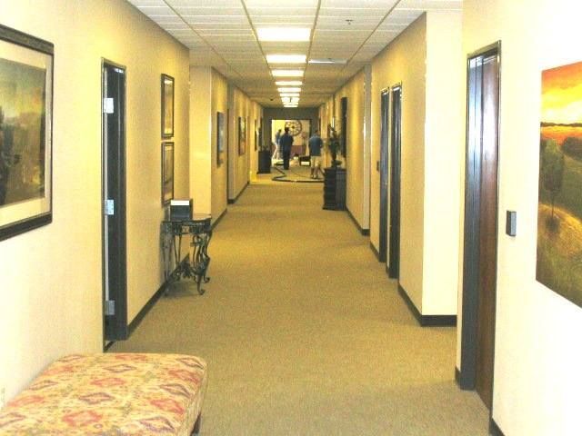 Long, beige hallway with doors on both sides, art, and a decorative bench.