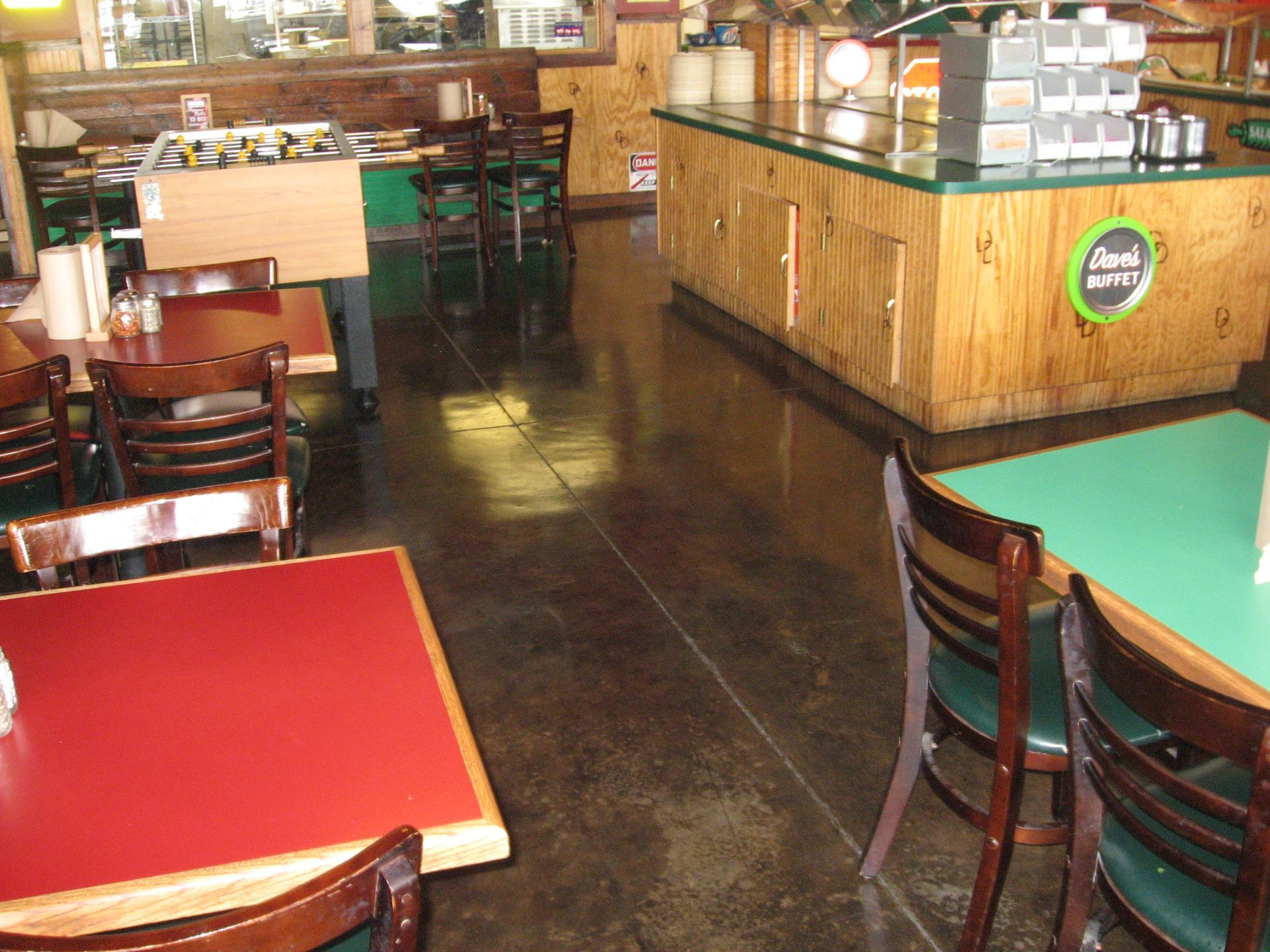 Interior of a diner with red and green tables, wooden chairs, and a wood-paneled counter.