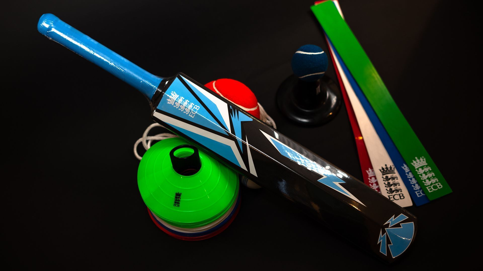 A cricket bat is sitting on top of a green ball.