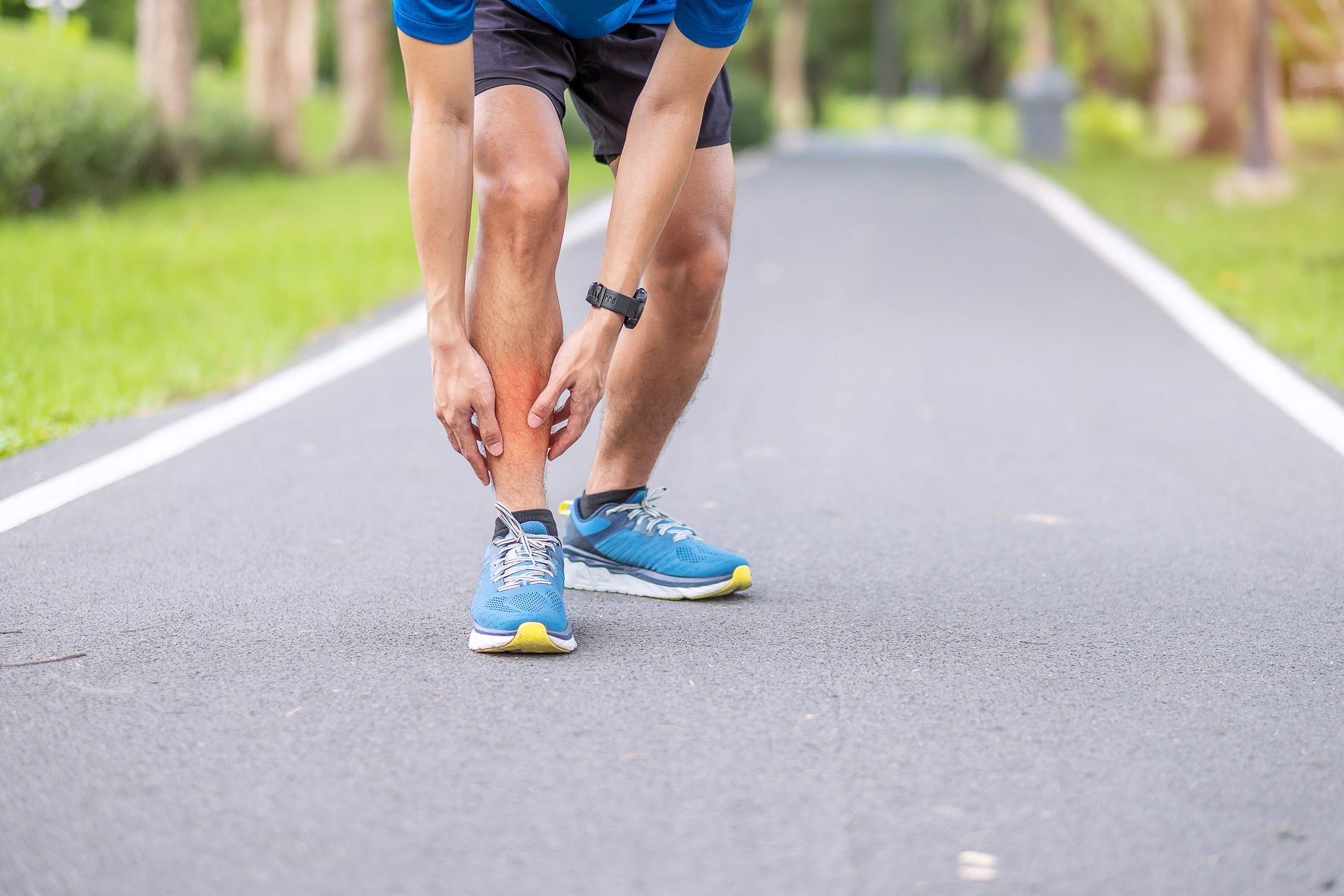 A man is tying his shoelaces on a road.