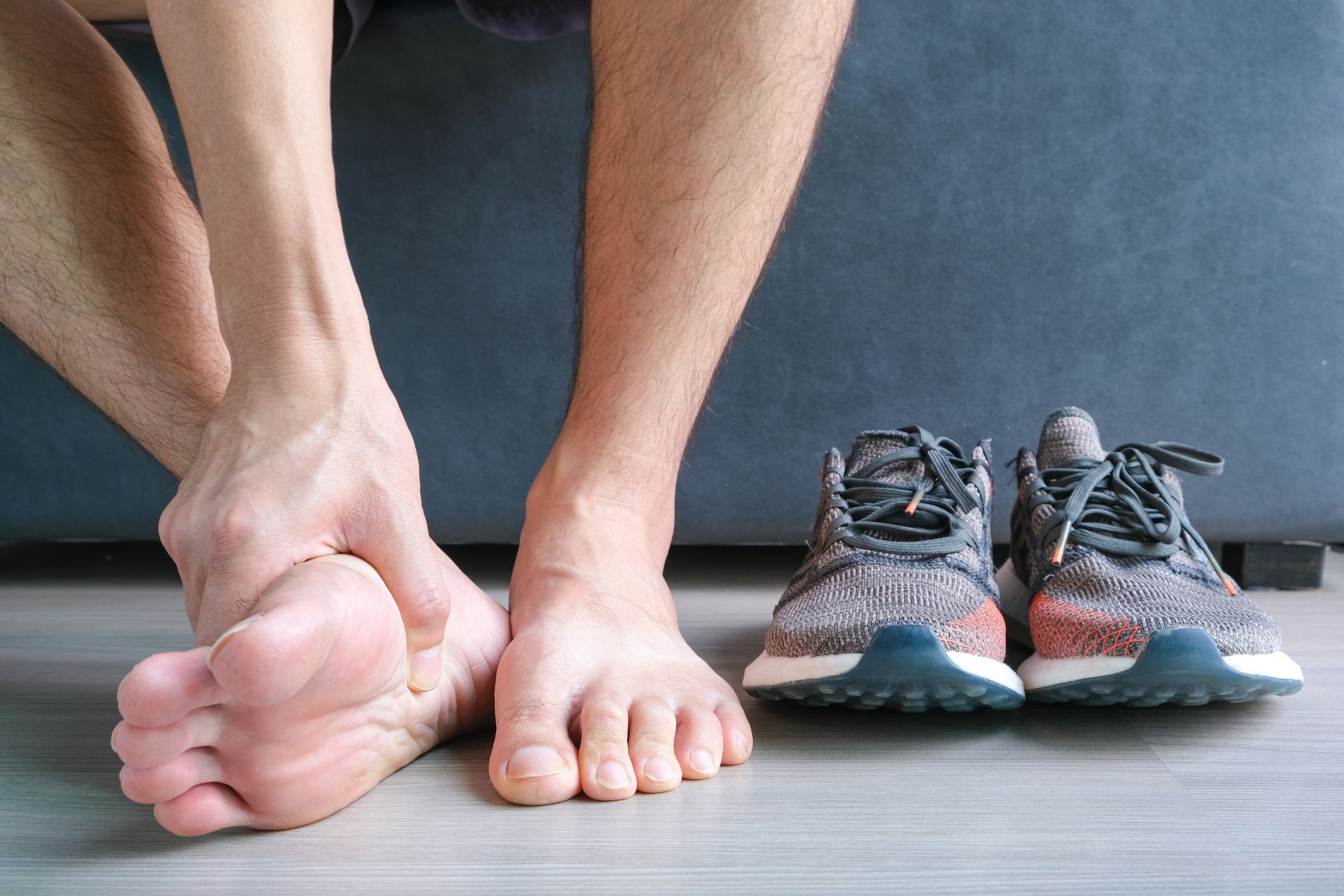 A man is sitting on a couch with his feet up next to a pair of shoes.