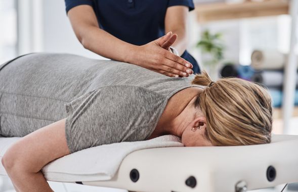 A woman is laying on a table getting a massage from a doctor.