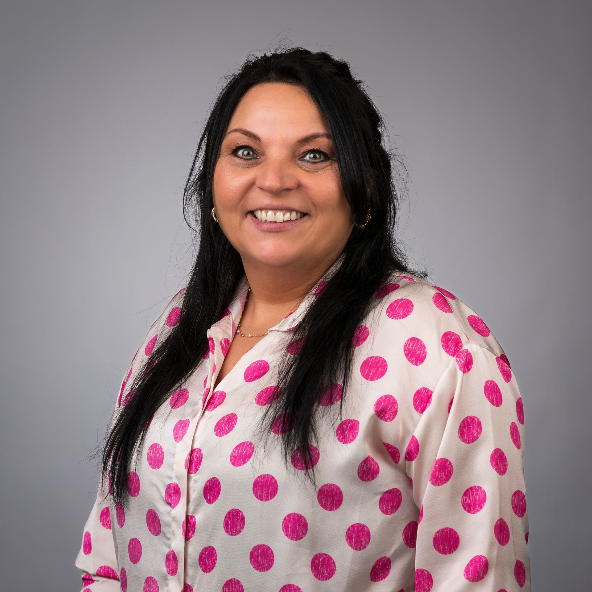 Een vrouw draagt een paars jasje en lacht.