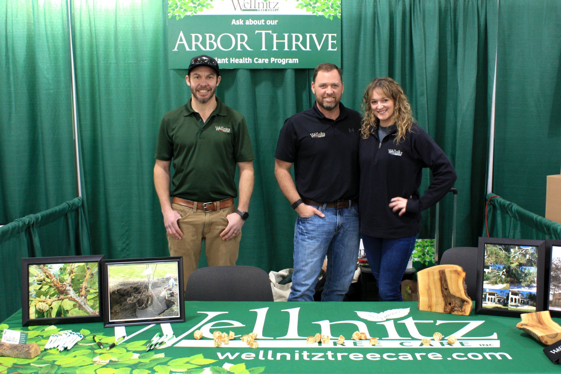 Three people are standing in front of a table that says arbor thrive