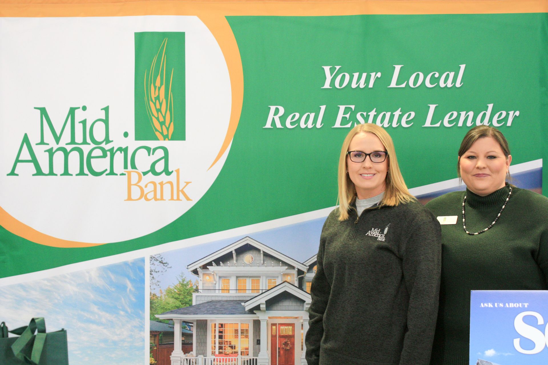 Two women standing in front of a sign that says your local real estate lender