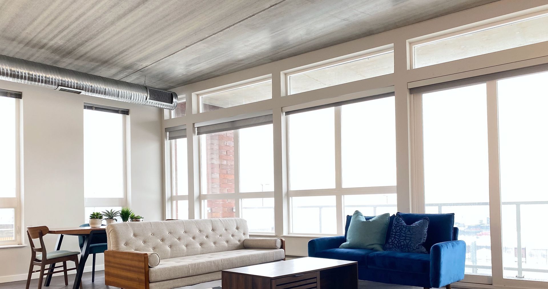 A living room with a couch , table , chairs and lots of windows.