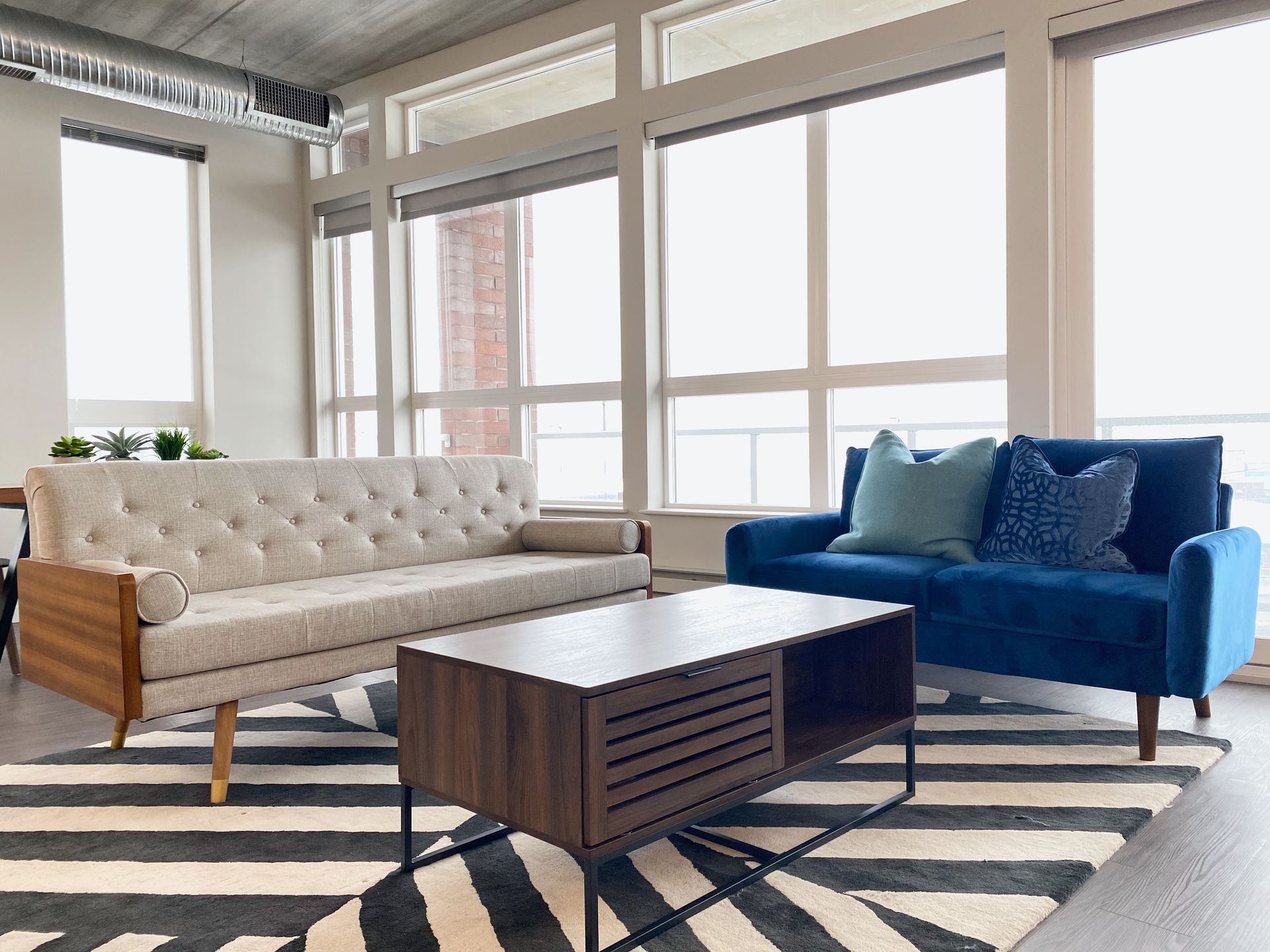 A living room with a couch , chair , coffee table and rug.
