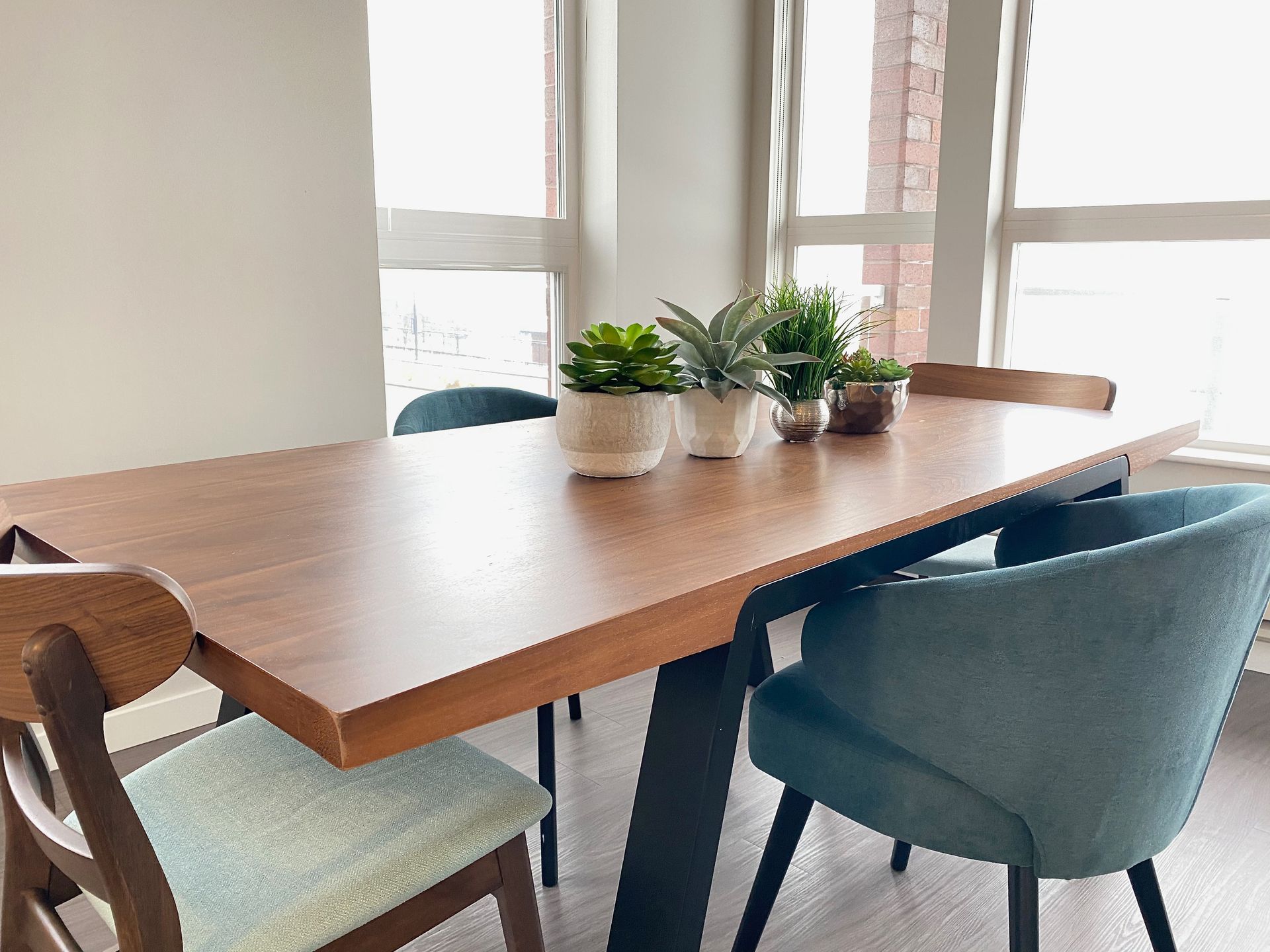 A dining room table with chairs and potted plants on it.