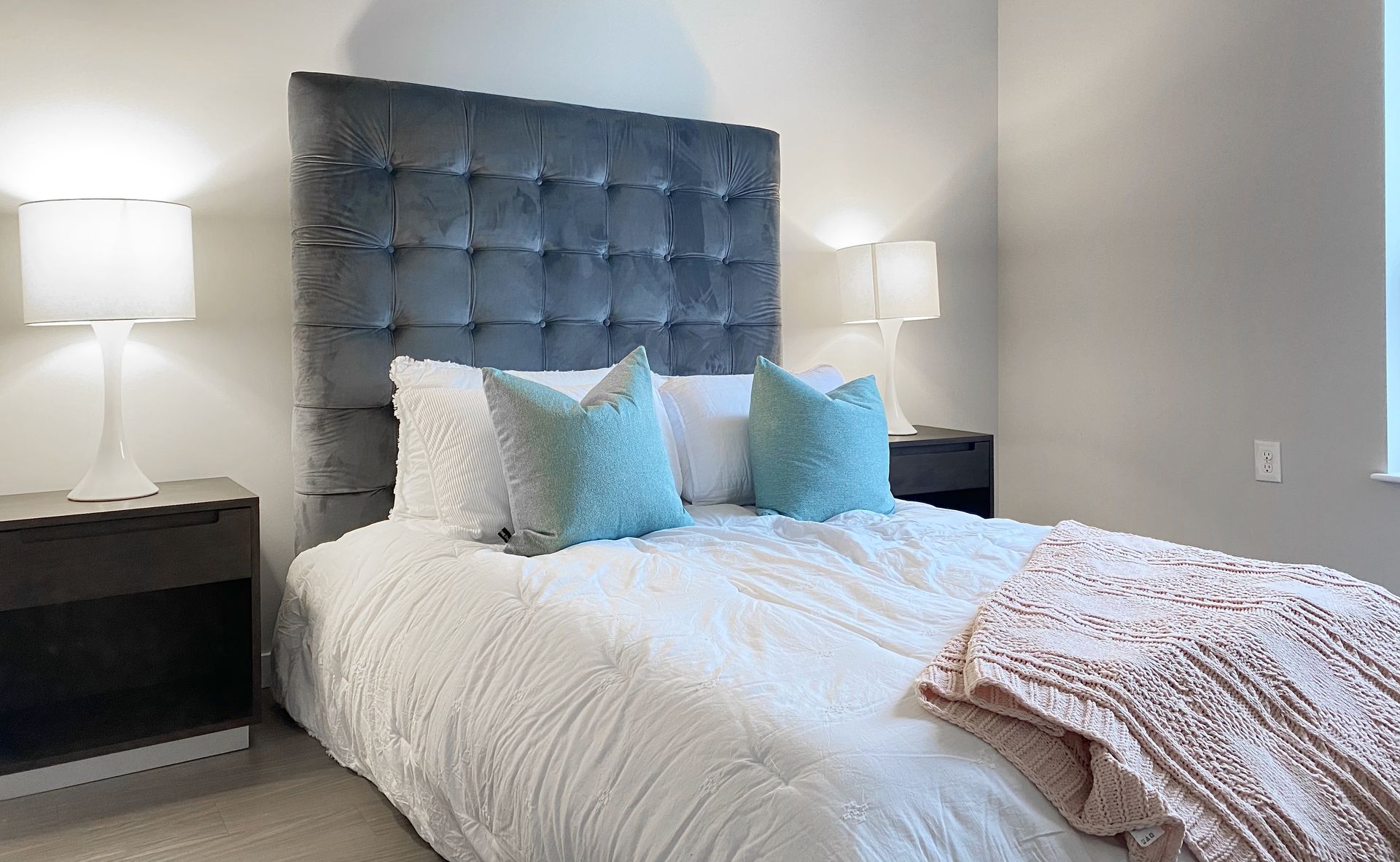 A bedroom with a bed , nightstands , lamps and a window.