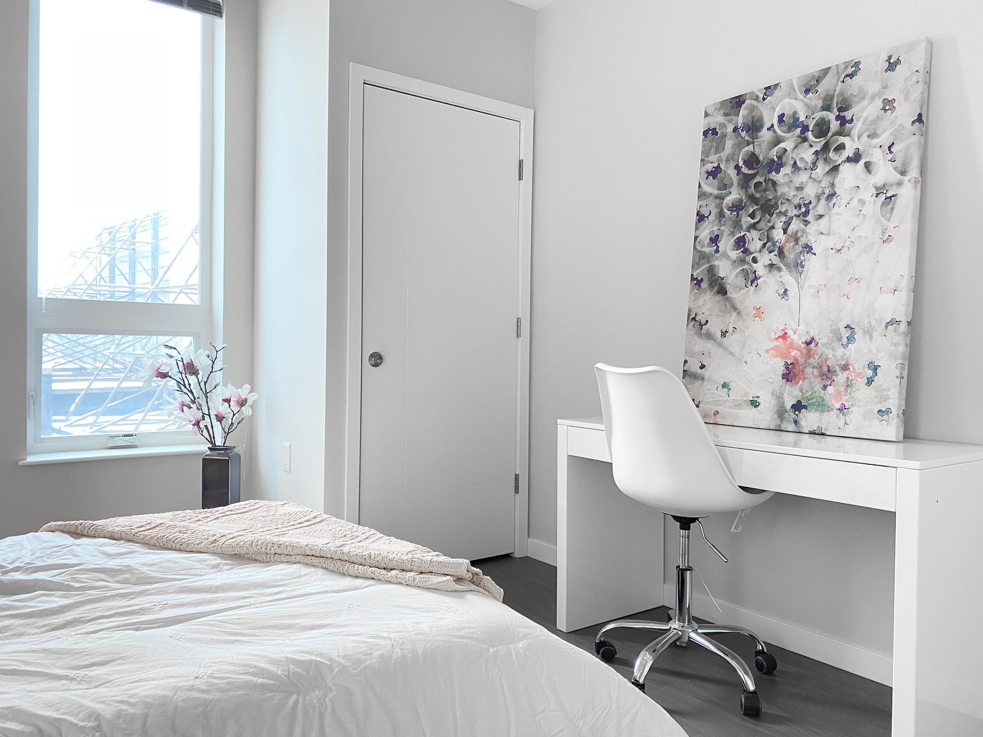 A bedroom with a bed , desk , chair and painting on the wall.