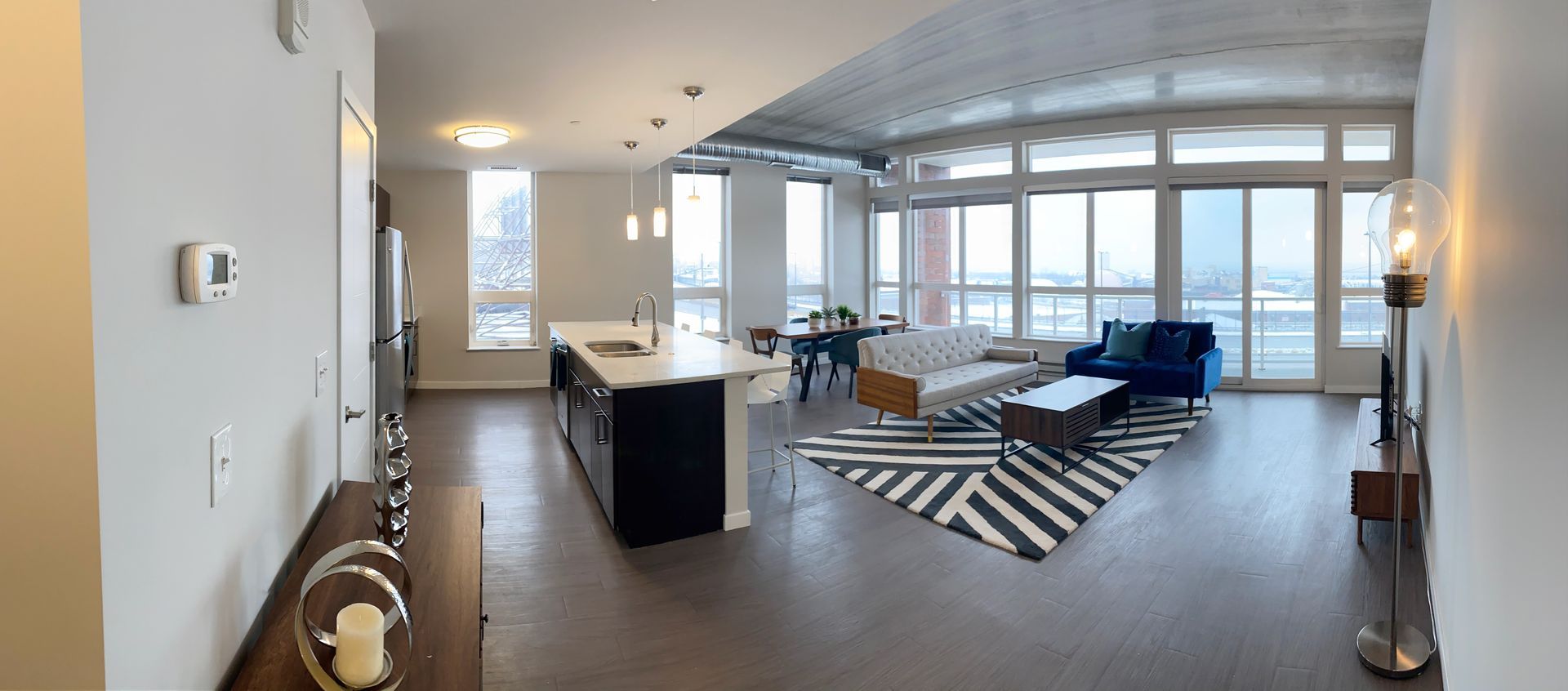 A large living room with a lot of windows and a black and white rug.