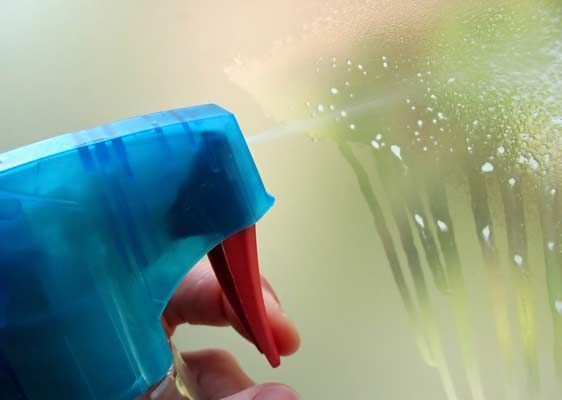 Una persona está rociando una botella de spray en una ventana.